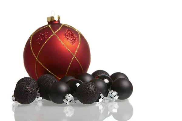 Um grande vermelho e muitas pequenas bolas de Natal pretas espelhadas no fundo branco — Fotografia de Stock