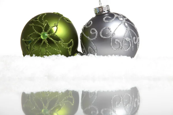 Two Christmas tree balls in the snow mirrored on white background — Stock Photo, Image