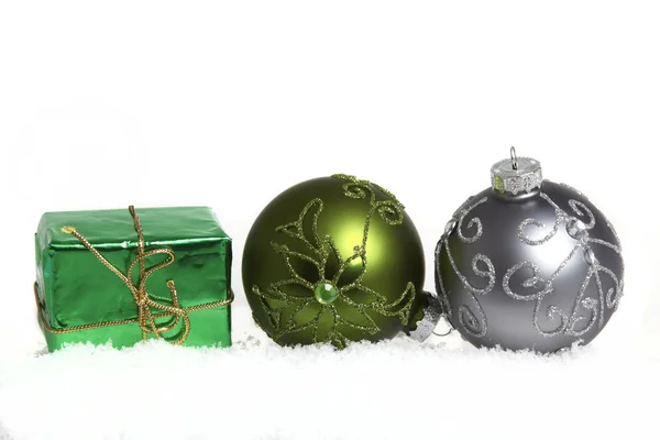 Two Christmas tree balls and a small gift in the snow on white background — Stock Photo, Image