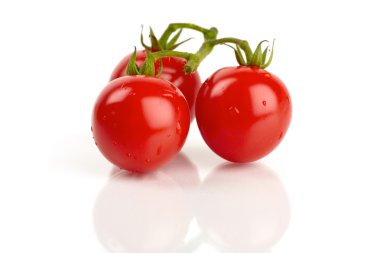 Three fresh cocktail tomatoes mirrored and covered with water droplets clipart