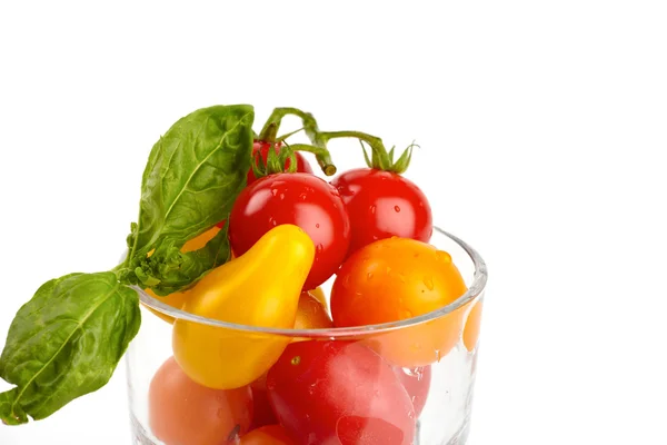 Un vaso lleno de coloridos tomates orgánicos pequeños en frente de fondo blanco — Foto de Stock