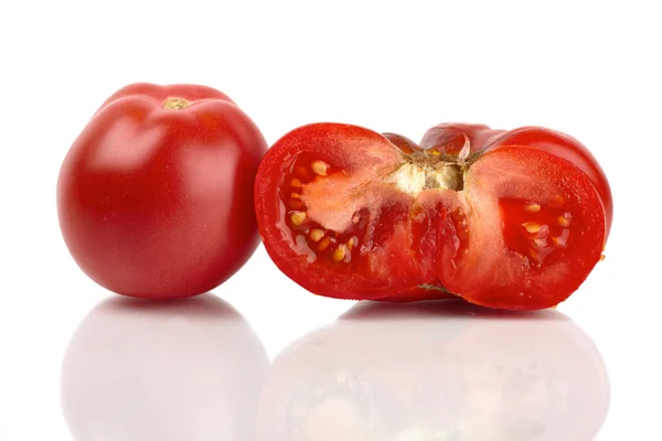 Two large organic tomatoes, one whole and one half mirrored in front of white background — Stock Photo, Image