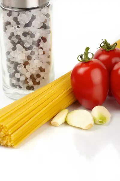Makaron spaghetti z pomidorami i czosnkiem na białym tle — Zdjęcie stockowe