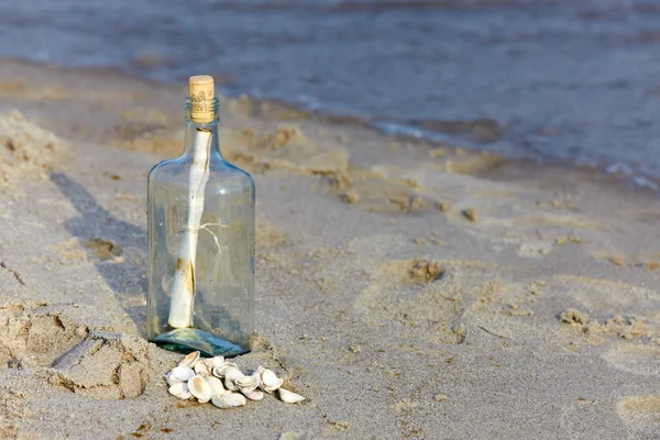 在海滩上的瓶子里的帮助消息 — 图库照片
