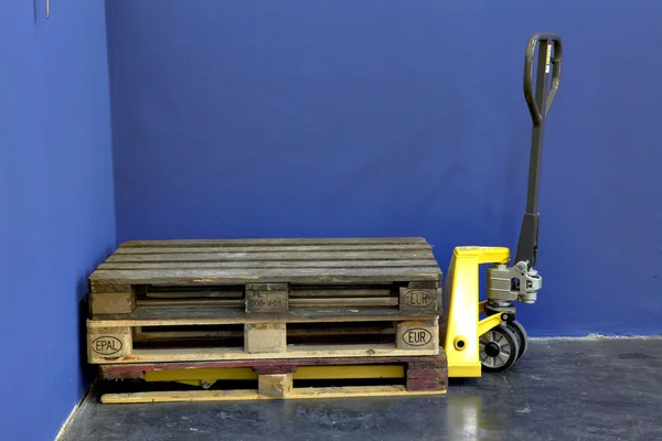 Tre pallet di legno su un carrello elevatore giallo in una sala industriale — Foto Stock