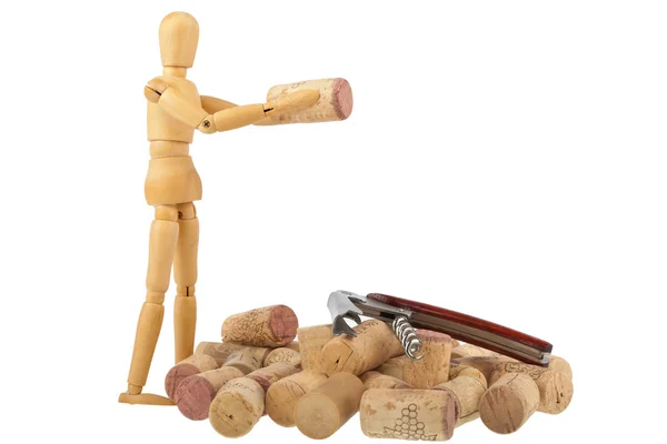 Wooden puppet stands in front of a bunch corks with corkscrew — Stock Photo, Image
