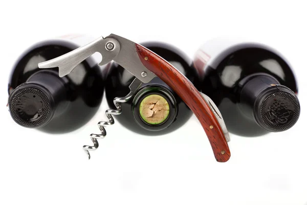 Corkscrew opened in front of a three wine bottle — Stock Photo, Image