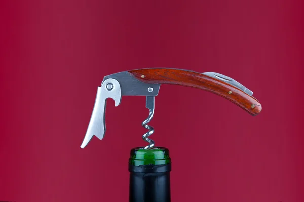 Kırmızı bir arka plan önünde bir şarap şişesi üzerinde zarif şarap çatal bıçak takımı — Stok fotoğraf