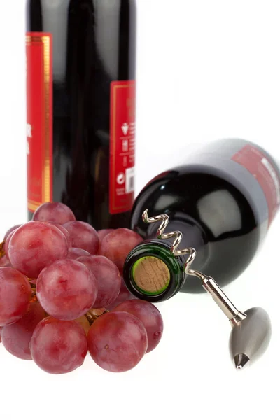 Due bottiglie di vino con cavatappi e uva su fondo bianco — Foto Stock