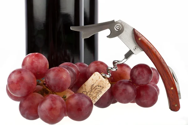 Corkscrew aberto e uvas na frente de uma garrafa de vinho — Fotografia de Stock