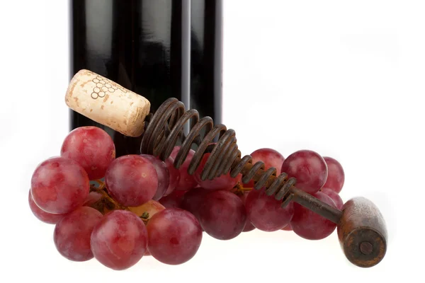 Older Corkscrew and grapes in front of a wine bottle — Stock Photo, Image