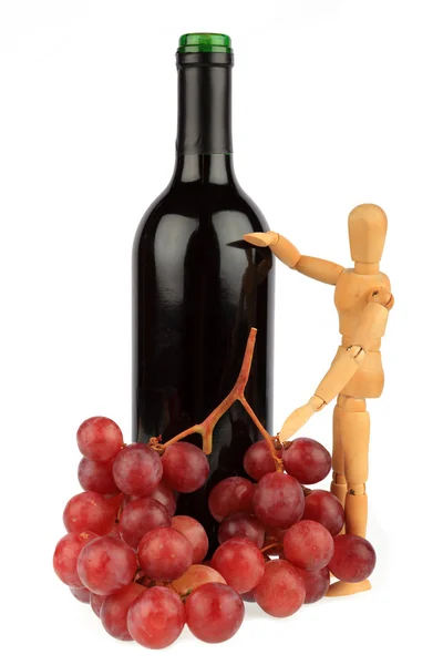 Ξύλινη μαριονέτα που στέκεται δίπλα σε ένα μπουκάλι κρασί με σταφύλια — Φωτογραφία Αρχείου