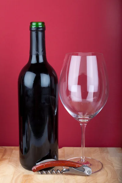 Şarap şişesi, cam ve ahşap tahta üzerinde bir tirbuşon. — Stok fotoğraf