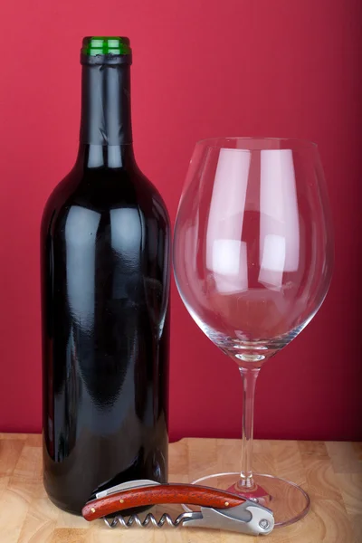 Láhev na víno, sklo a vývrtka na dřevěném prkénku. — Stock fotografie