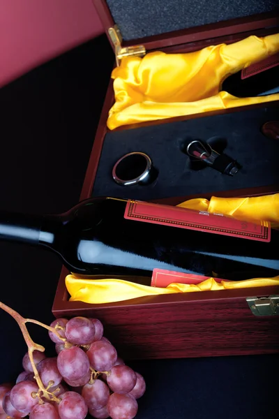 Příbory a láhev vína víno zdobené v hnědé dřevěné krabičky s hrozny — Stock fotografie