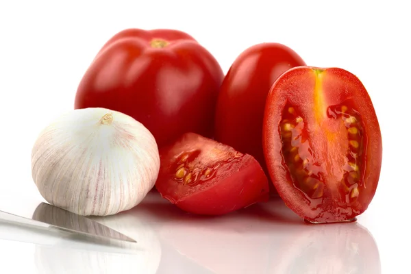 Свежие помидоры с луком чеснока и ножом на белом фоне — стоковое фото