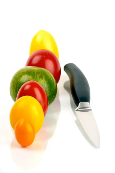 Vários tomates orgânicos em série com uma faca — Fotografia de Stock