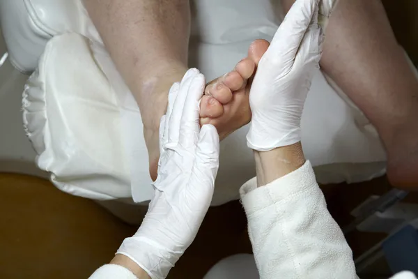 Un pedicurista le da a una mujer una reflexología de piernas y pies — Foto de Stock