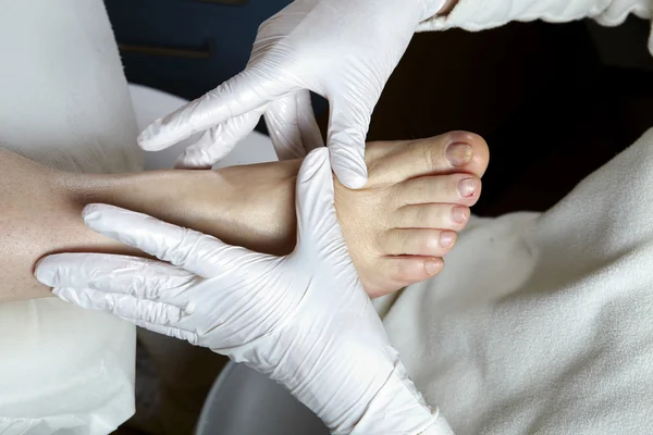 Egy pedikűrösünk ad egy nő lábát, és láb reflexológia — Stock Fotó