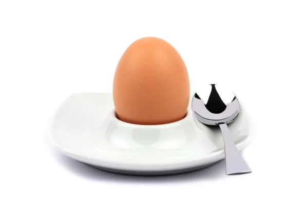 Brunt egg i en eggebeger med skje foran hvit bakgrunn – stockfoto