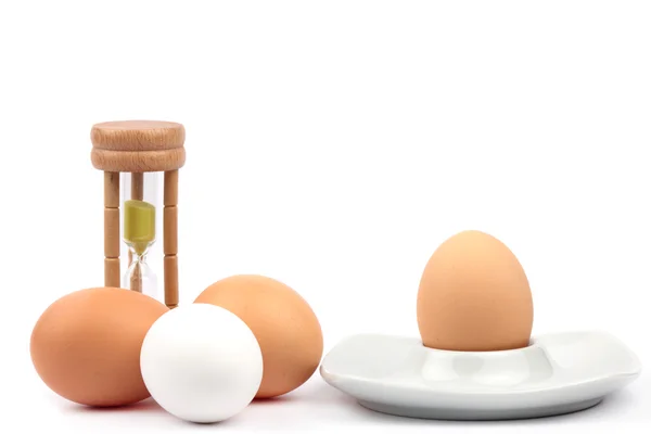 Chicken eggs and egg cups and eggtimer — Stock Photo, Image