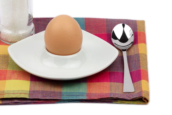 Breakfast egg in an egg cup with spoon and salt mill — Stock Photo, Image