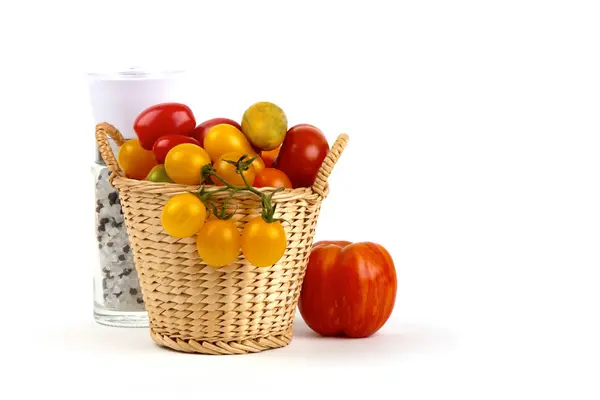 Molti pomodori biologici diversi nel cestino con sale e pepe mulino — Foto Stock