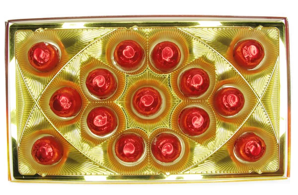 Snoepjes in rode envelopment in goud vak — Stockfoto