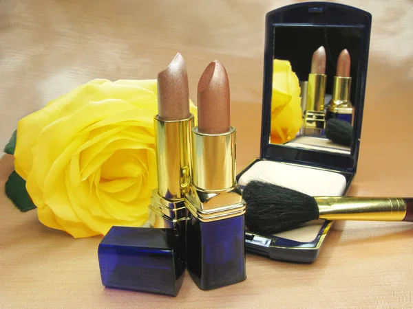 Two brown lipsticks powder and yellow rose — Stock Photo, Image