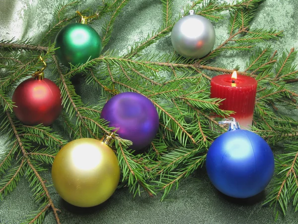 Christmas balls among fir branches with candle — Stock Photo, Image