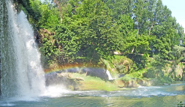 Panorama of waterfall falling into blue lagoon and rainbow — Stock Photo, Image
