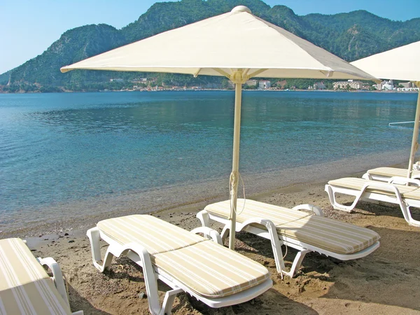 Playa con tiendas de sol y tumbonas — Foto de Stock