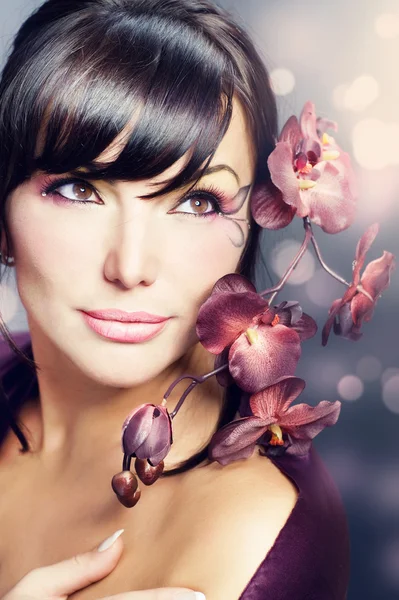 Schöne gesunde Frau mit Orchideenblume — Stockfoto