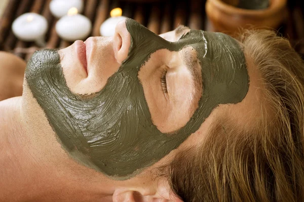 Spa. Homem bonito com uma máscara de lama em seu rosto — Fotografia de Stock
