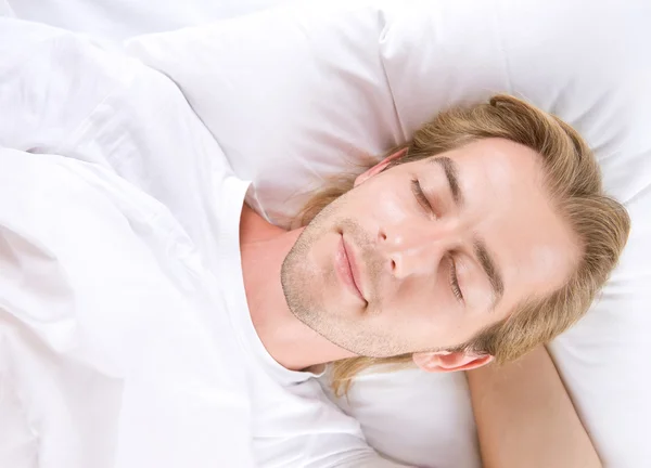 Junger Mann schläft in seinem Bett — Stockfoto