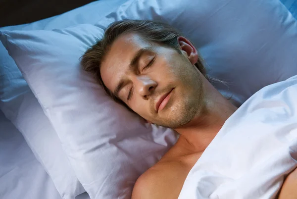 Unge man sover i sin säng — Stockfoto