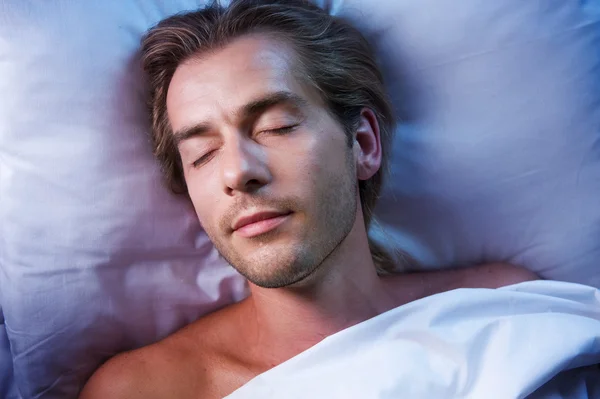 Junger Mann schläft in seinem Bett — Stockfoto