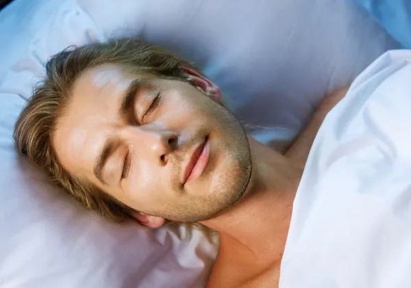 Unge man sover i sin säng — Stockfoto