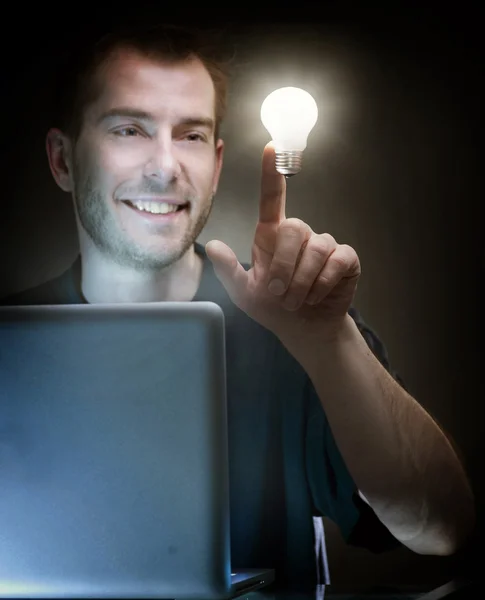 Молодой человек с ноутбуком и идеей лампочки — стоковое фото