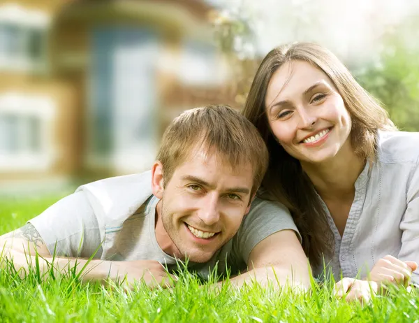 Casal feliz perto de sua casa. Família sorridente ao ar livre. Real Esta — Fotografia de Stock