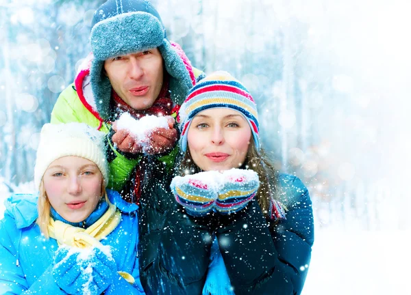 Familia Outdoors.Happy Familia con niño soplando Snow.Winter —  Fotos de Stock
