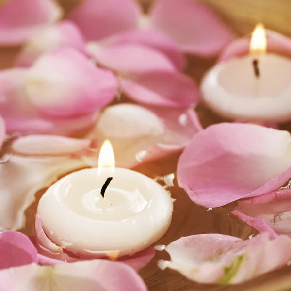 Spa zwevende kaarsen en roze bloemblaadjes in water — Stockfoto