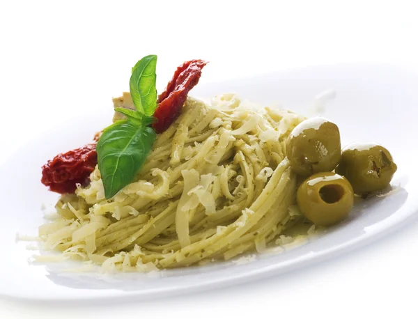 Włoski makaron z sosem pesto, suszone pomidory, oliwki, bazylia i — Zdjęcie stockowe
