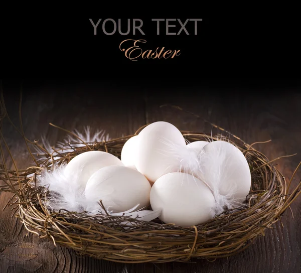 Easter Eggs in the nest over wooden background — Stock Photo, Image