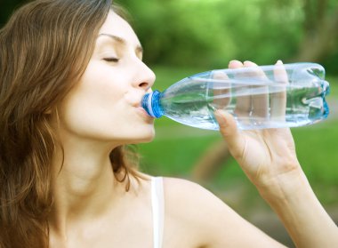 Genç sağlıklı kadın su şişesinden içiyor.