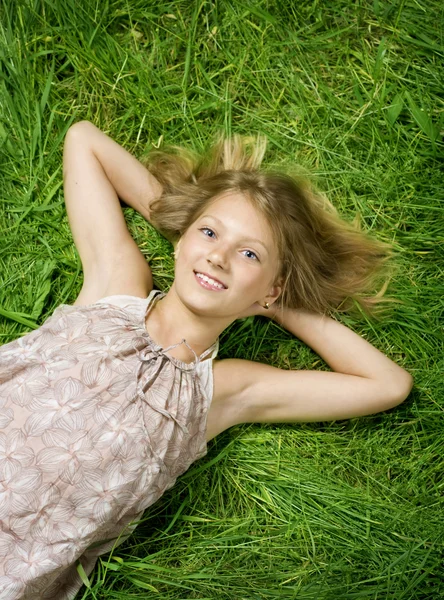 Симпатичная счастливая девочка, лежащая на зеленой грядке — стоковое фото