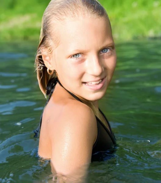 Glückliches süßes kleines Mädchen, das im Wasser schwimmt — Stockfoto