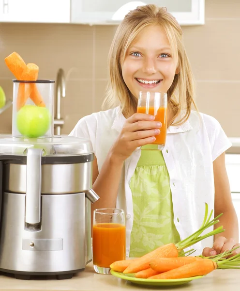 快乐女孩喝新鲜的胡萝卜和苹果汁。榨汁机 — 图库照片