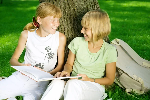 Dos niñas de la escuela leyendo el libro al aire libre —  Fotos de Stock
