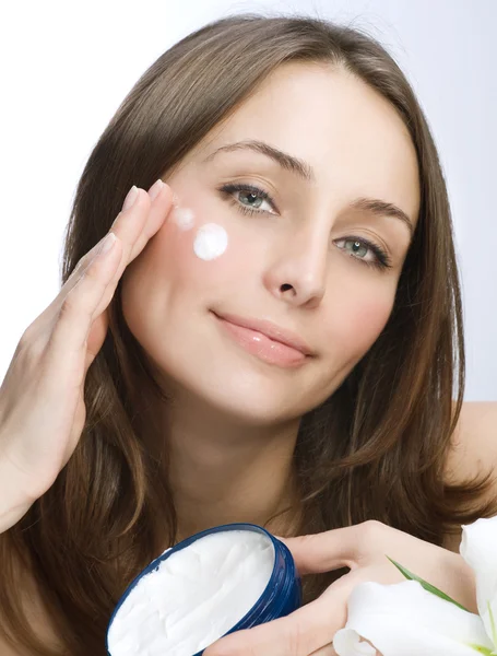 Hermosa mujer joven aplicando crema hidratante facial — Foto de Stock